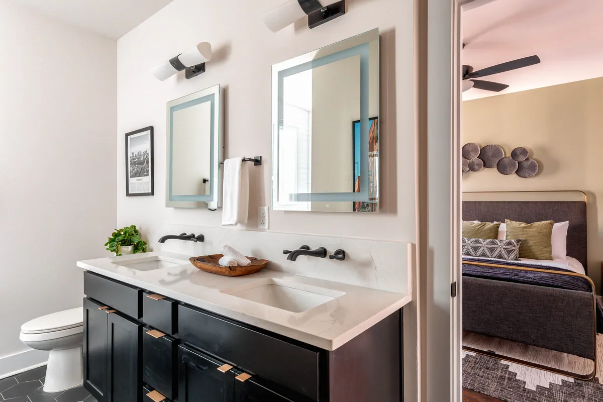 A contemporary bathroom featuring a double sink vanity with mirrors, dark cabinetry, and a decorative bowl with fresh towels. The clean, modern design invites relaxation and supports a pampering experience.