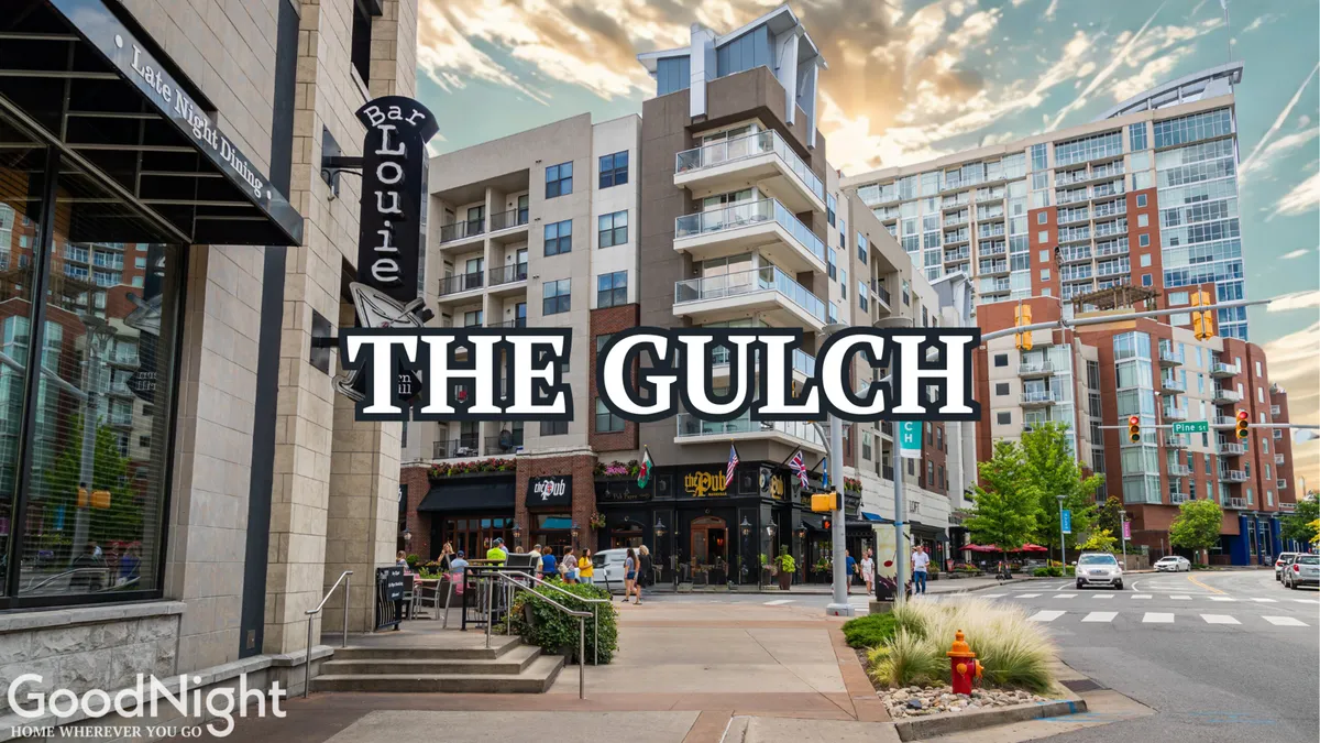 A lively city street scene featuring Bar Louie, apartment buildings, bustling pedestrian activity, and clear street signage. Outdoor seating areas are filled with people enjoying meals, while others stroll and take in the vibrant energy of the neighborhood. The street is framed by modern architecture with glimpses of the city skyline in the background.